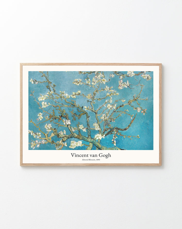 The Almond Blossom by Vincent van Gogh Poster hangs on a pristine white wall, featuring blooming almond branches against a vibrant blue sky, with the title and artists name elegantly displayed beneath the image.