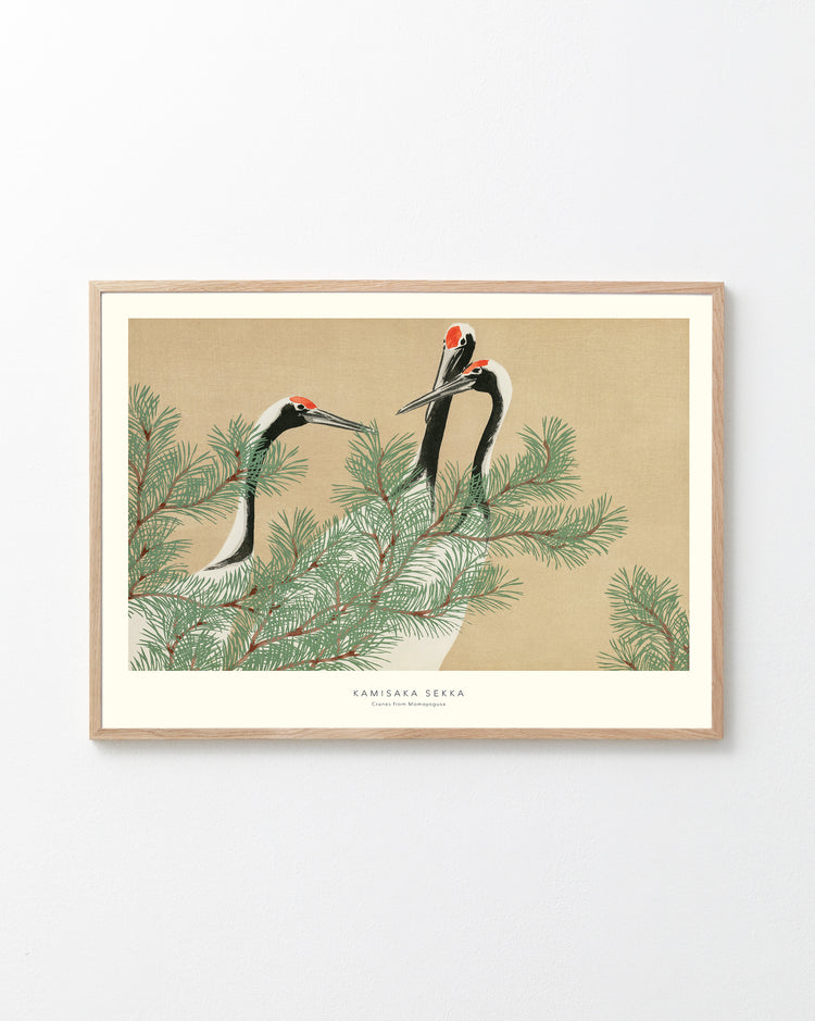 Framed artwork of cranes on a branch with a beige background