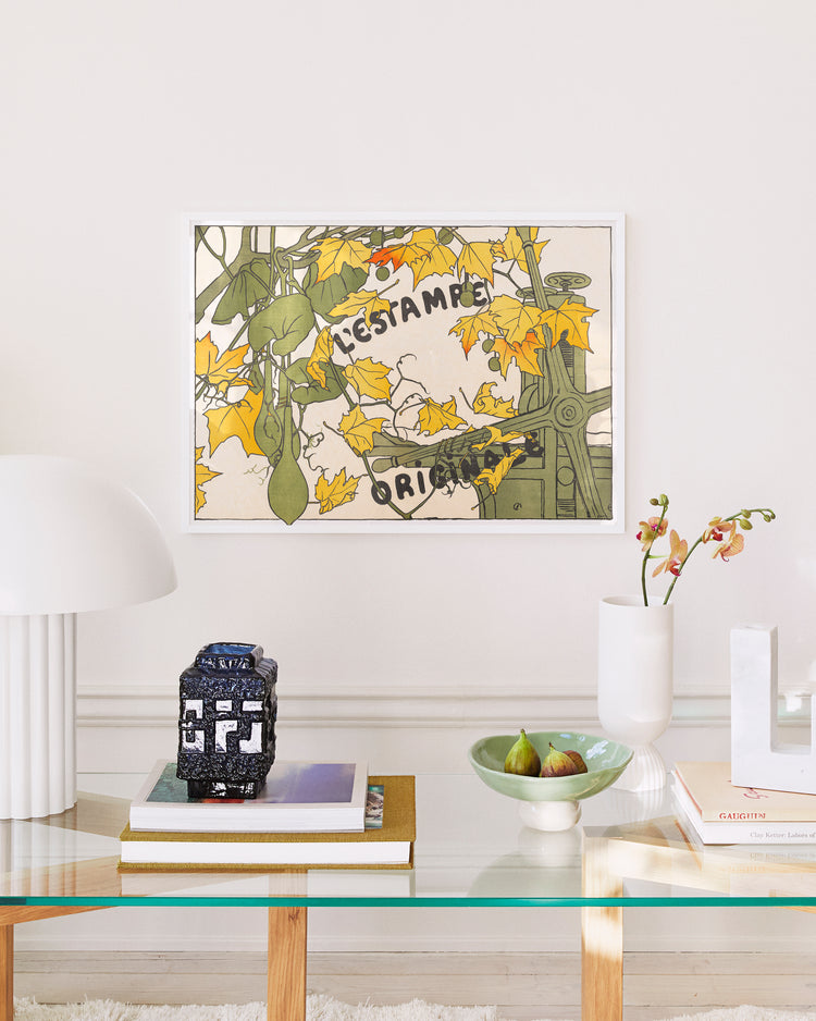 Decorative wall art with floral design and text above a glass table with books and a vase.