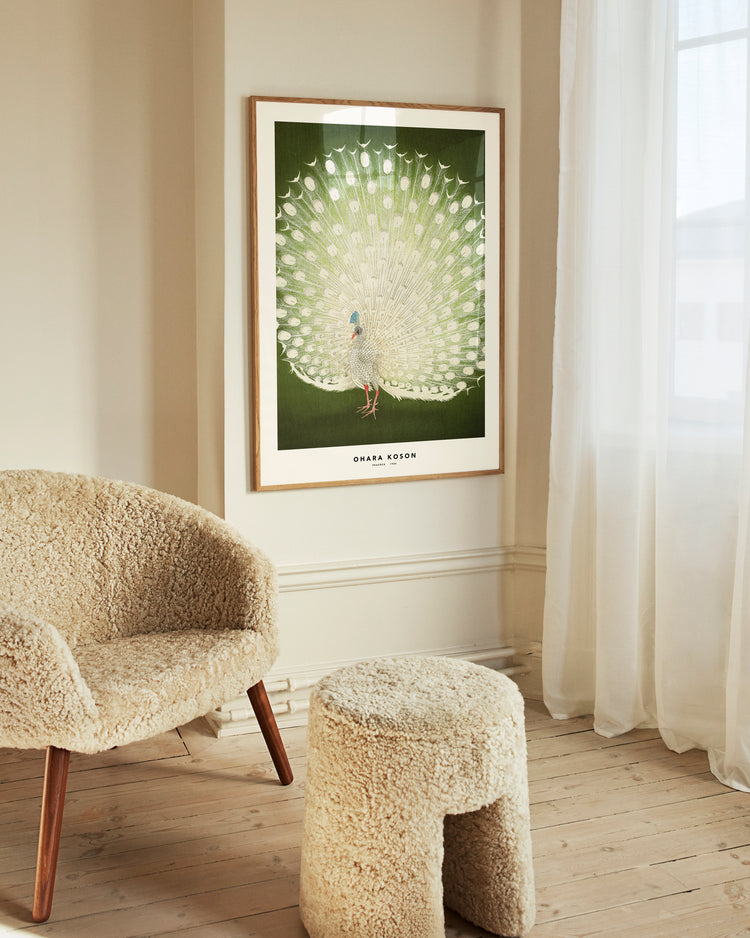 Furry chair and stool in a room with a framed artwork of a peacock on the wall.