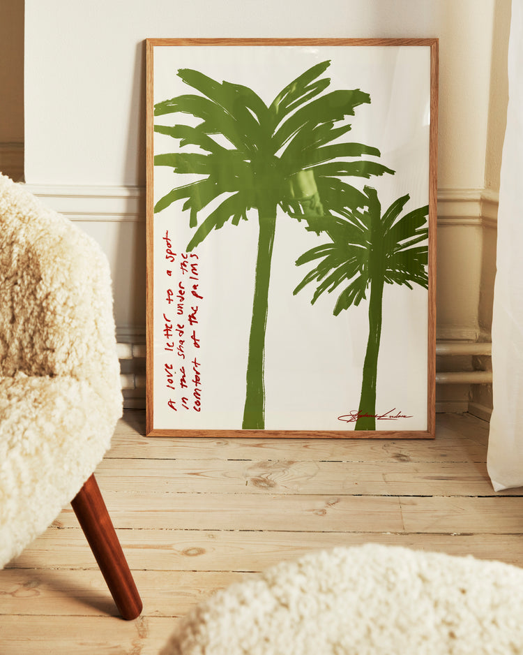 The Spot in the Shade Poster features two green palms symbolizing tropical tranquility, leaning against a wall on a light wooden floor, with handwritten red text in the lower left corner and a beige textured chair for quiet reflection.