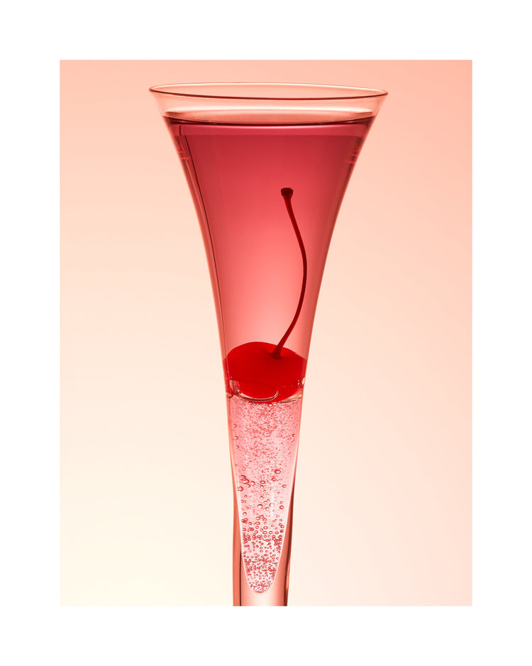 An eye-catching still life photograph showcasing a close-up of a drink adorned with a delectable cherry against a vibrant pink background. White border.
