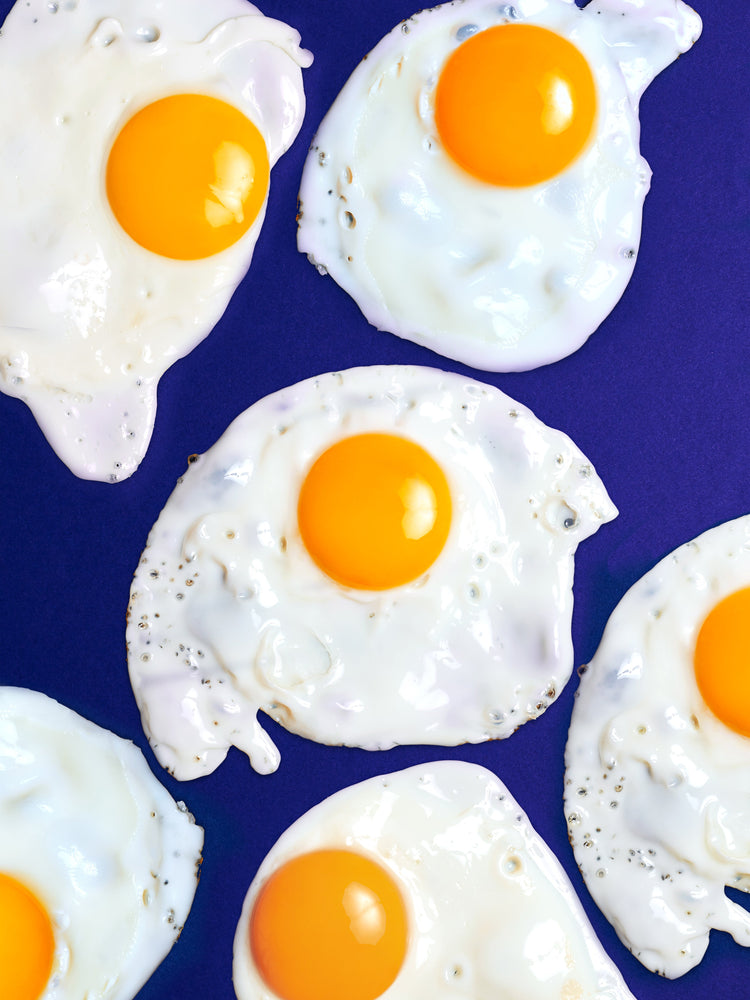 A still life photograph of eggs on a vibrant blue background.