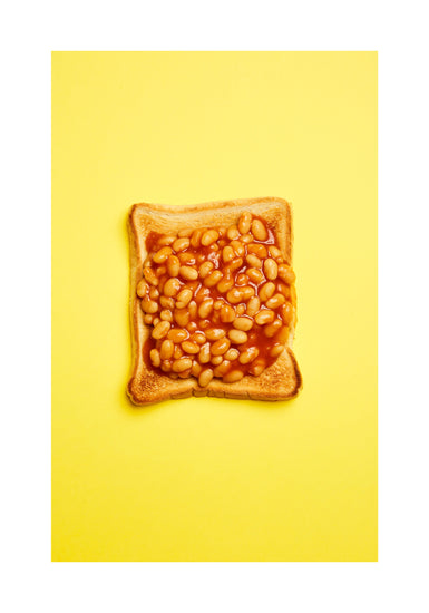 A still life photograph featuring baked beans on toast set against a vibrant yellow background. White border.