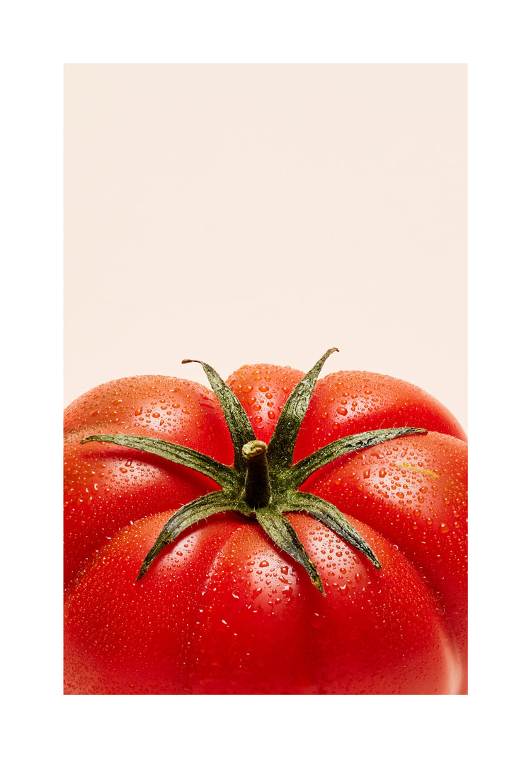 A close-up photograph features a vibrant red tomato adorned with delicate water droplets set against a clean white backdrop. White border.