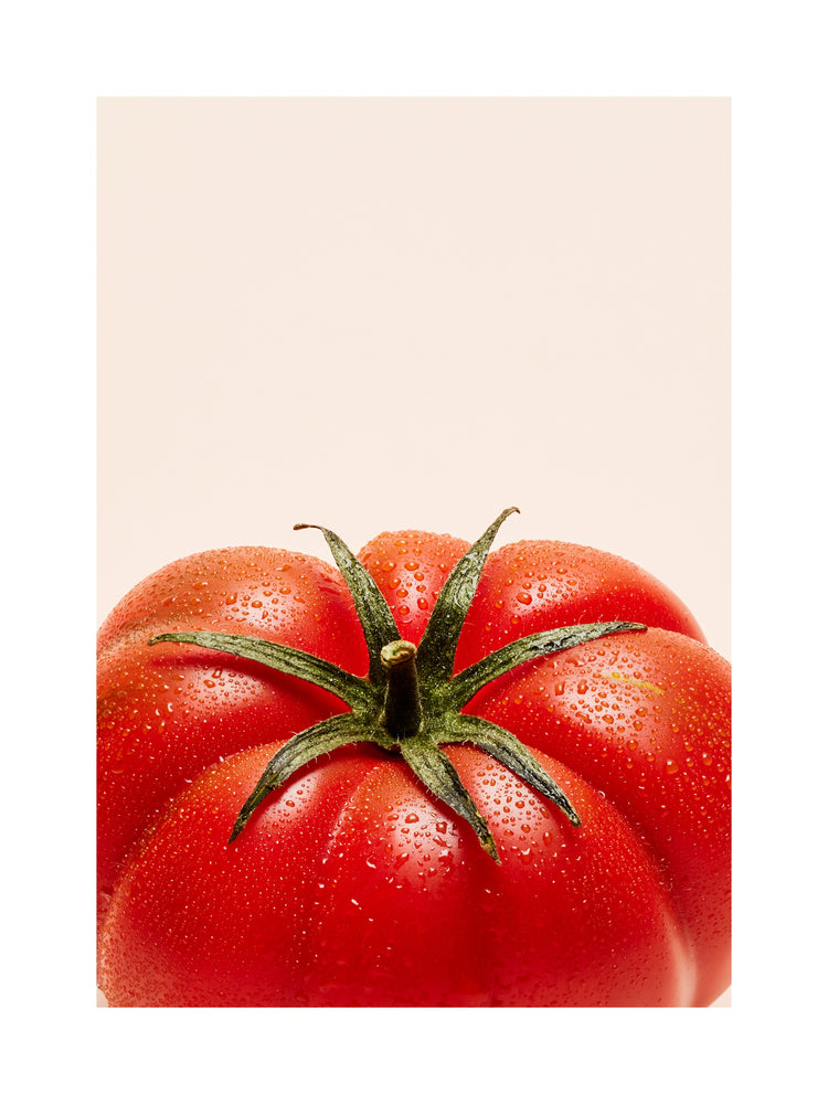 A close-up photograph features a vibrant red tomato adorned with delicate water droplets set against a clean white backdrop. White border.