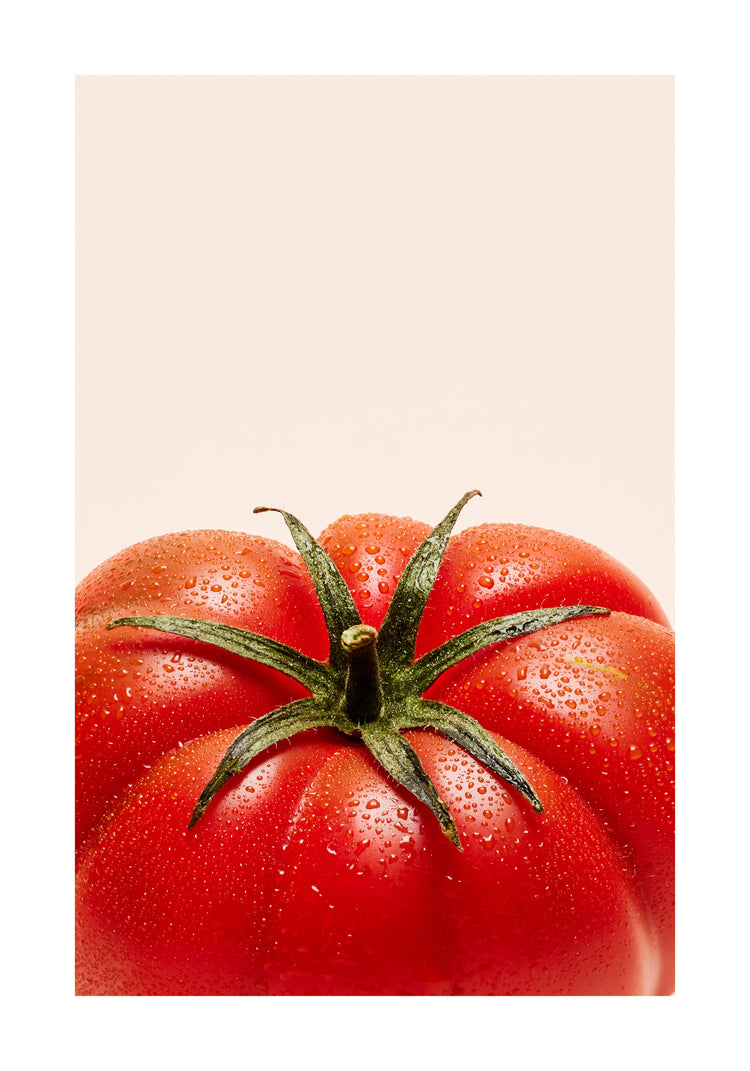 A close-up photograph features a vibrant red tomato adorned with delicate water droplets set against a clean white backdrop. White border.