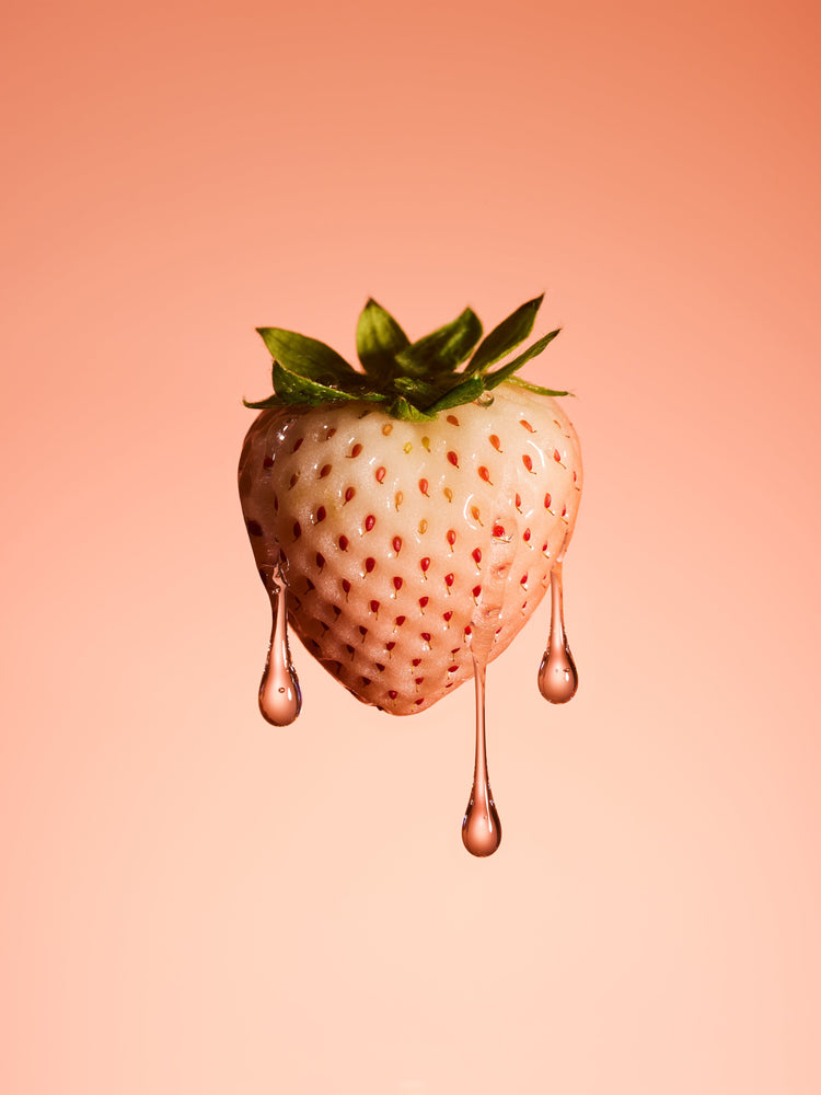 A stilllife photograph of a flawless white strawberry on a pretty pink background.