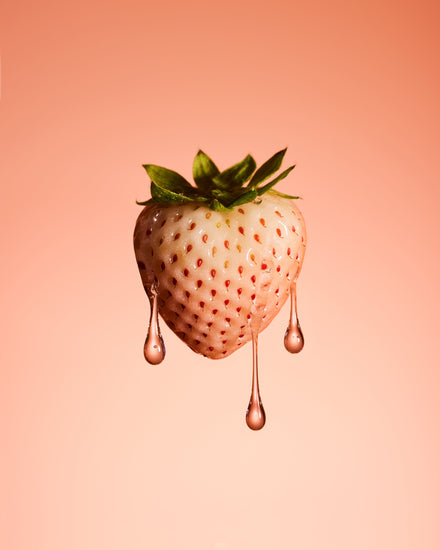 A stilllife photograph of a flawless white strawberry on a pretty pink background.