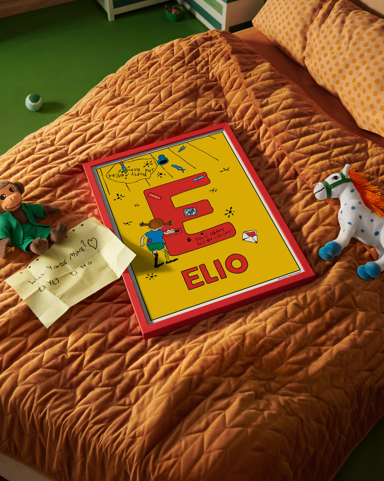 Pippi Longstocking name poster with the letter E and the name Elio, placed on a neatly made bed in a bright kids’ room.