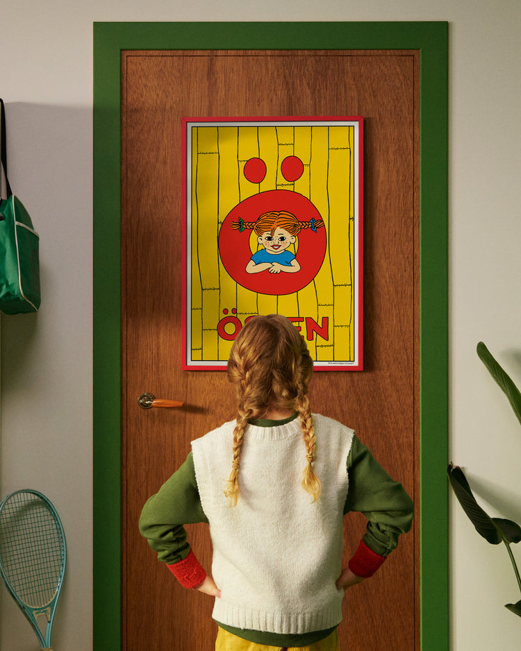 Pippi Longstocking personalised poster featuring the letter Ö hanging on a door, with a child curiously looking at the artwork.