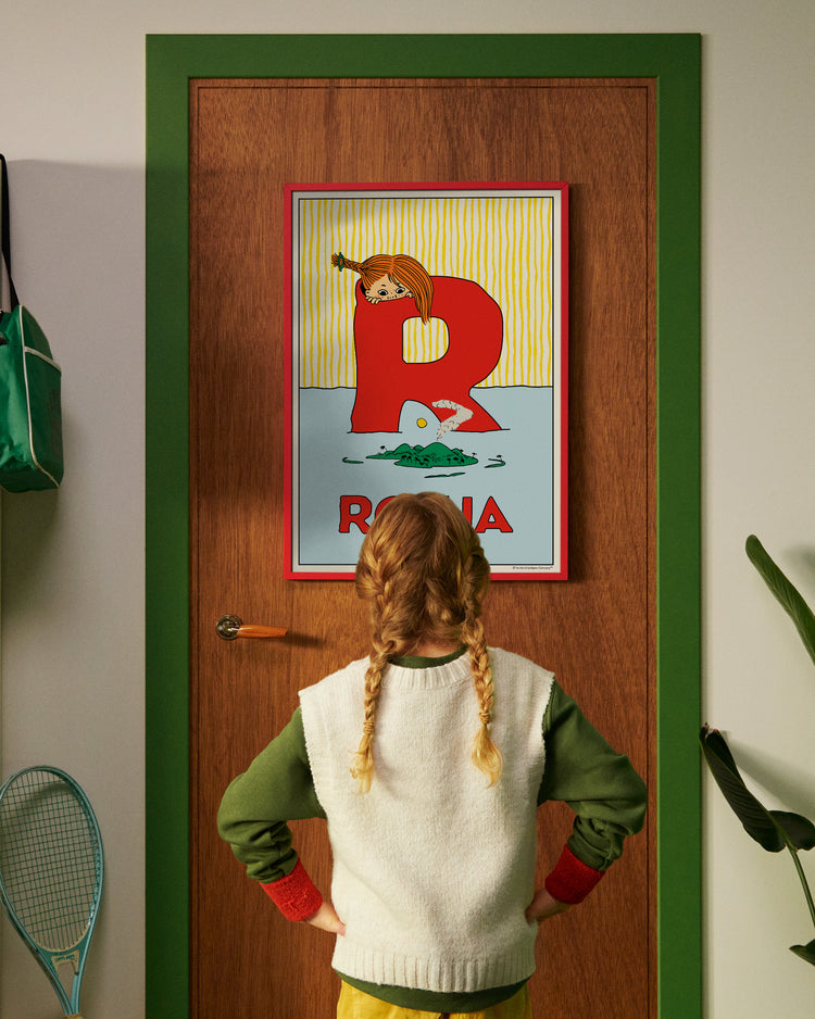 Pippi Longstocking personalised poster featuring the letter R hanging on a door, with a child curiously looking at the artwork.
