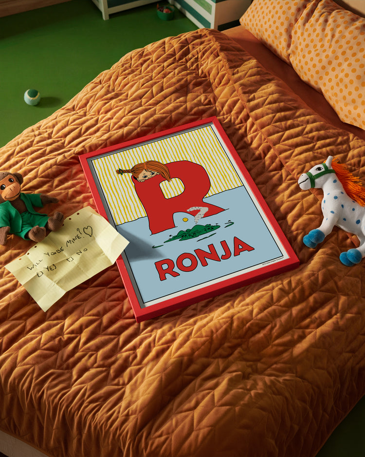 Pippi Longstocking name poster with the letter R and the name Ronja, placed on a neatly made bed in a bright kids’ room.