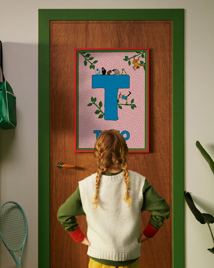 Pippi Longstocking personalised poster featuring the letter T hanging on a door, with a child curiously looking at the artwork.