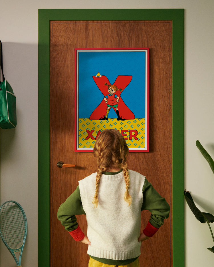 Pippi Longstocking personalised poster featuring the letter X hanging on a door, with a child curiously looking at the artwork.