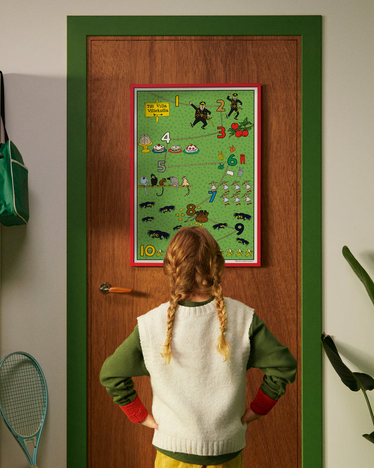 A child looks at a Pippi Longstocking numbers poster hanging on a door.