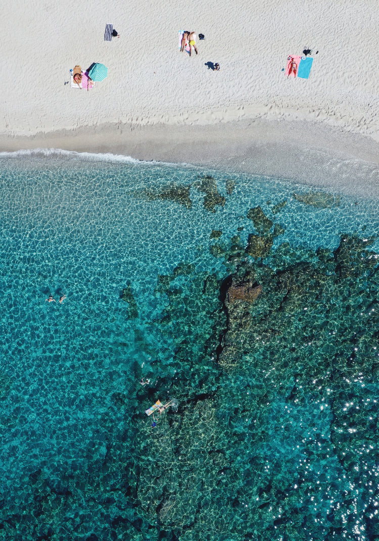 Drone photograph of a white sandbank and a turquoise ocean sparkling in the sun.