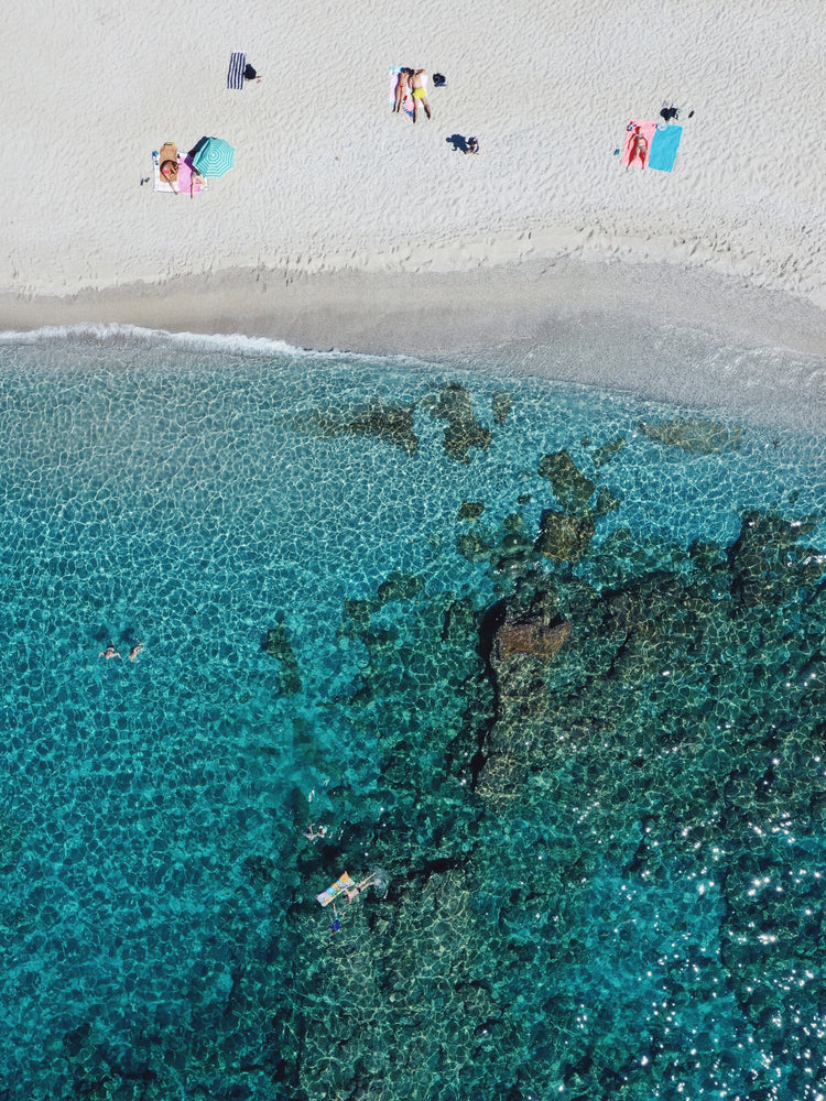 Drone photograph of a white sandbank and a turquoise ocean sparkling in the sun.