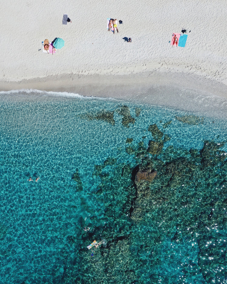 Drone photograph of a white sandbank and a turquoise ocean sparkling in the sun.