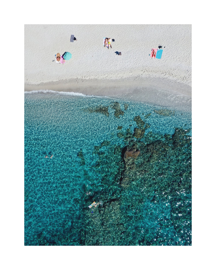 Drone photograph of a white sandbank and a turquoise ocean sparkling in the sun.