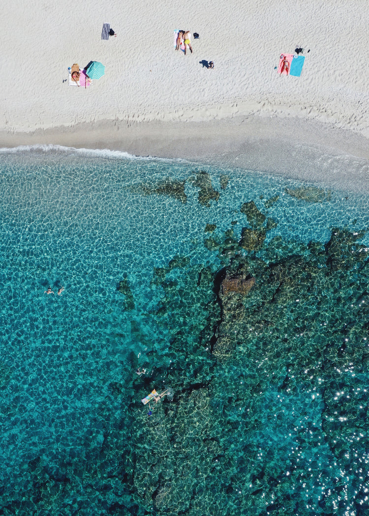 Drone photograph of a white sandbank and a turquoise ocean sparkling in the sun.