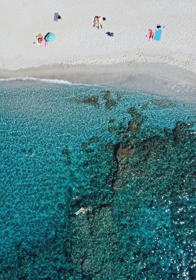Drone photograph of a white sandbank and a turquoise ocean sparkling in the sun.