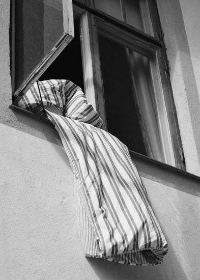 Striped sheets hanging out from an open window.