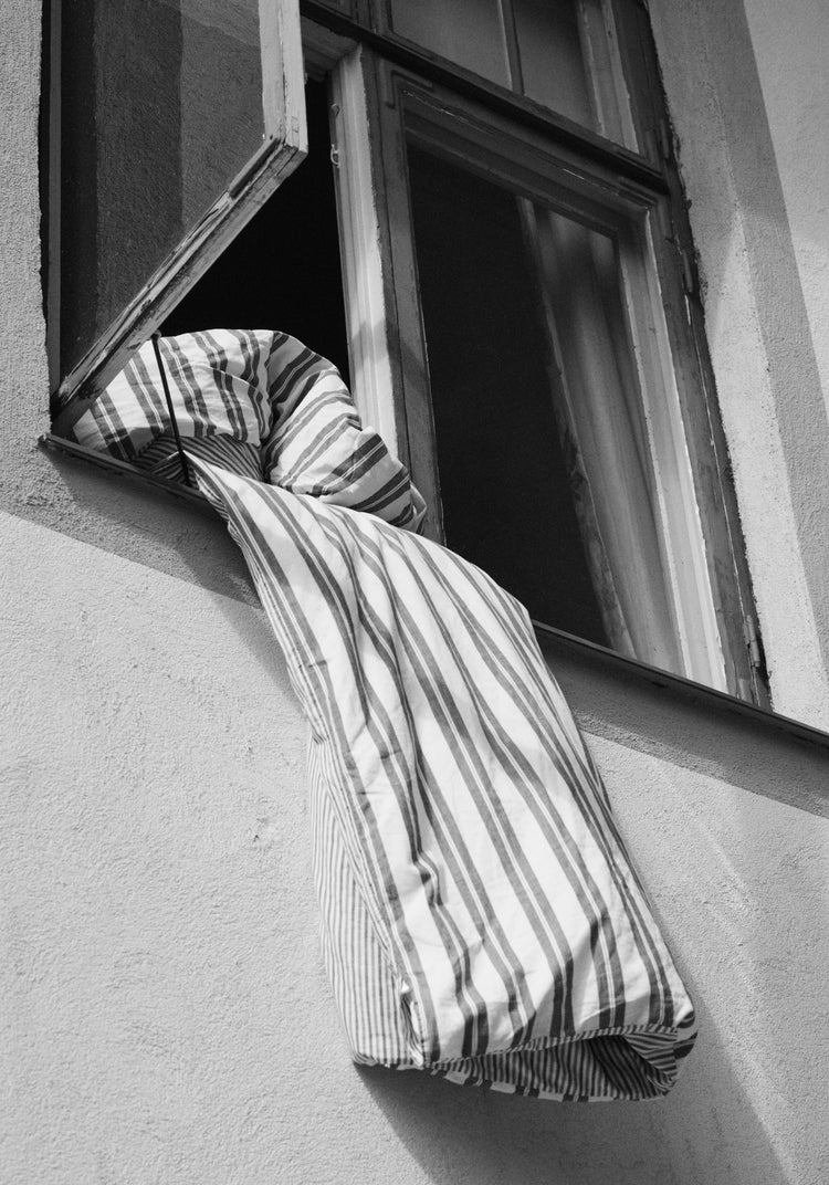 Striped sheets hanging out from an open window.