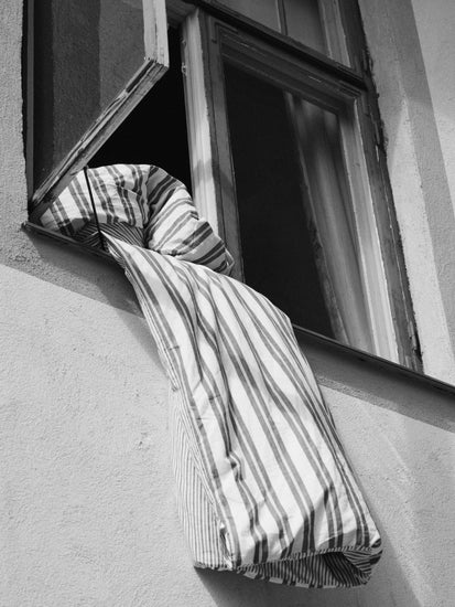 Striped sheets hanging out from an open window.