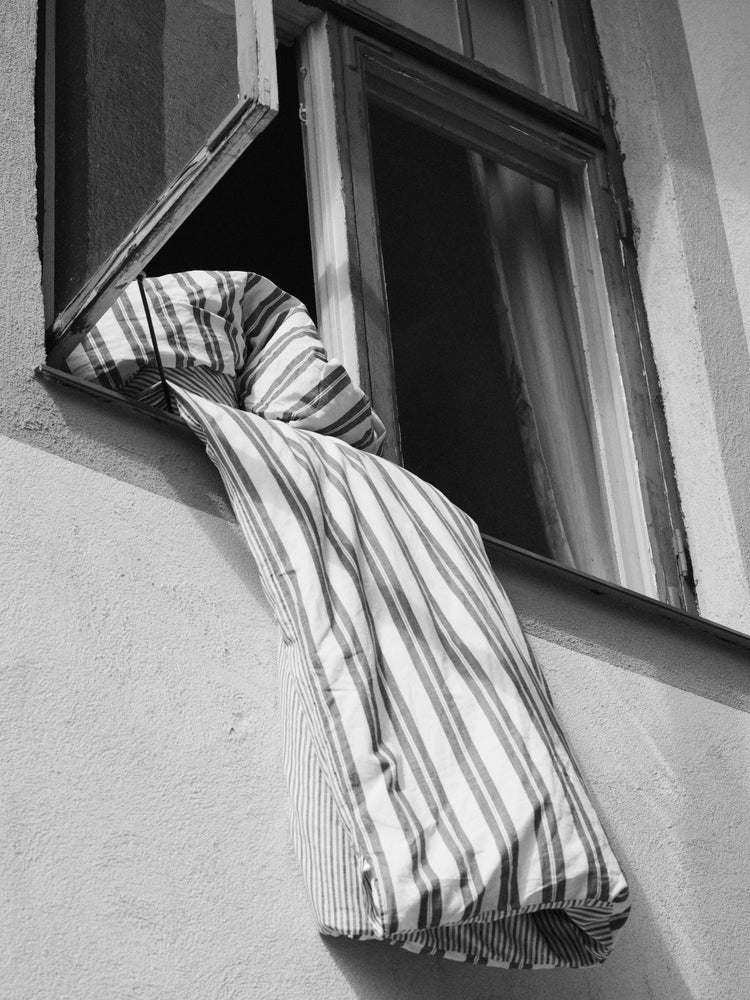 Striped sheets hanging out from an open window.