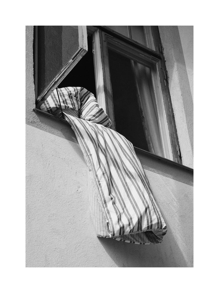 Striped sheets hanging out from an open window.