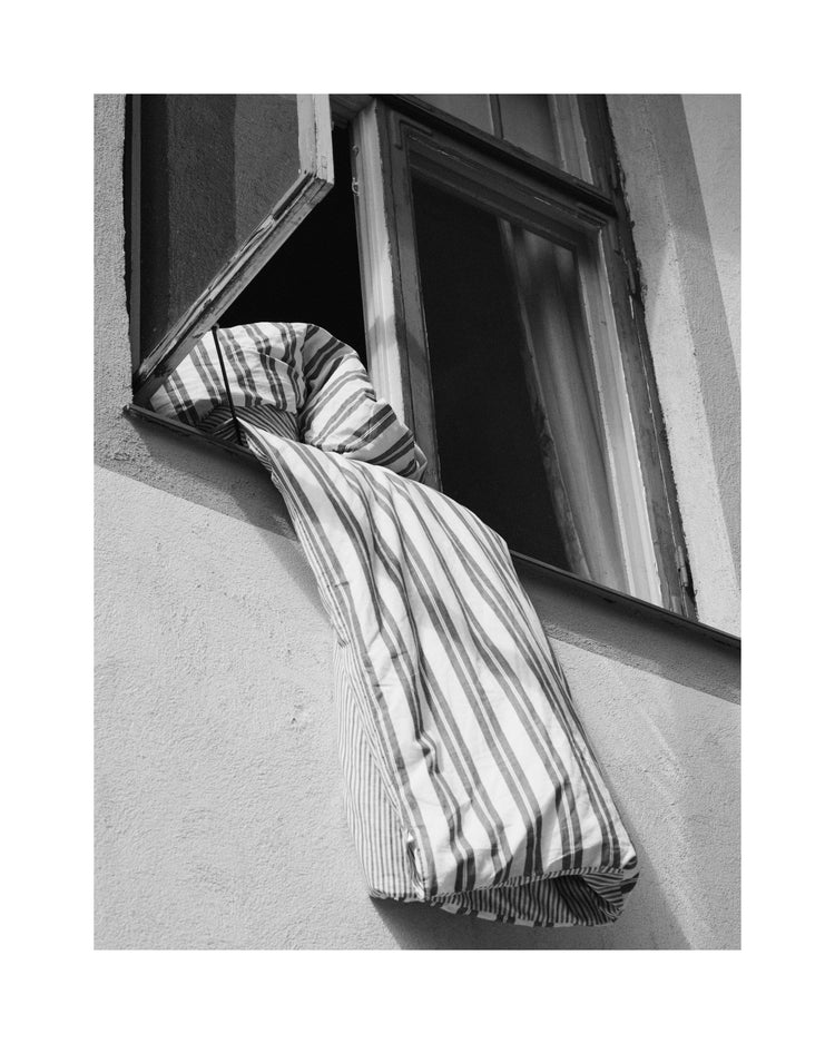 Striped sheets hanging out from an open window.