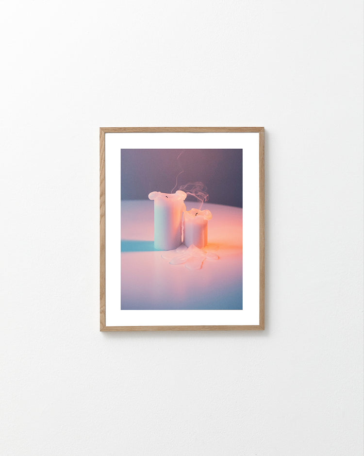 Two recently blown out candles on a white table.