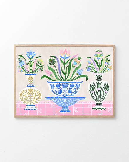 The Ceramics Poster, inspired by Swedish kurbits art, features a blue intricately designed central vase flanked by two smaller white and gold vases, all brimming with vibrant flowers and foliage on a pink patterned surface.