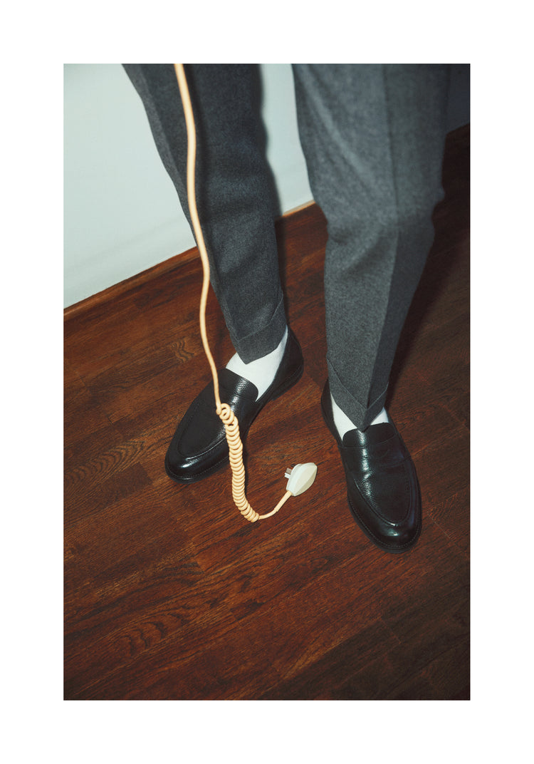A man with dress shoes and slacks holding a yellow landline.