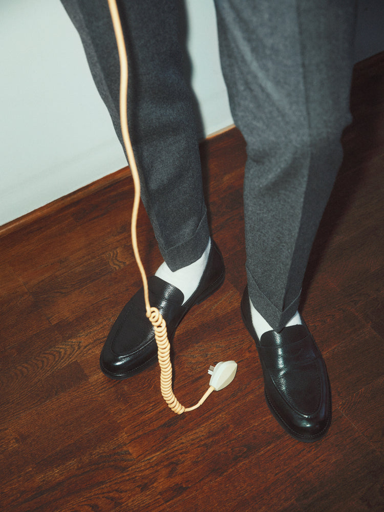 A man with dress shoes and slacks holding a yellow landline.