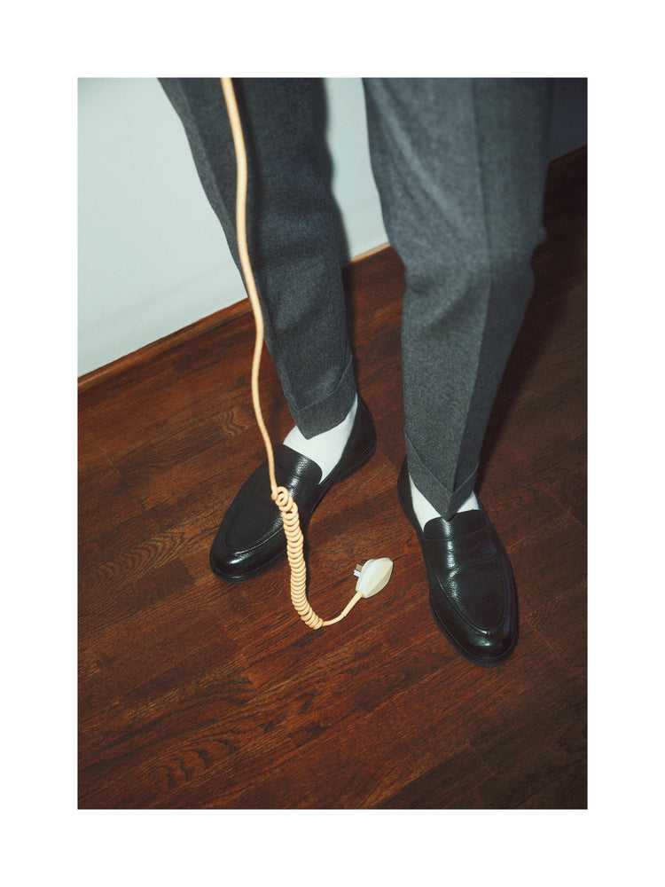 A man with dress shoes and slacks holding a yellow landline.