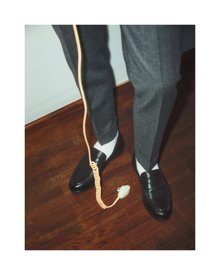 A man with dress shoes and slacks holding a yellow landline.