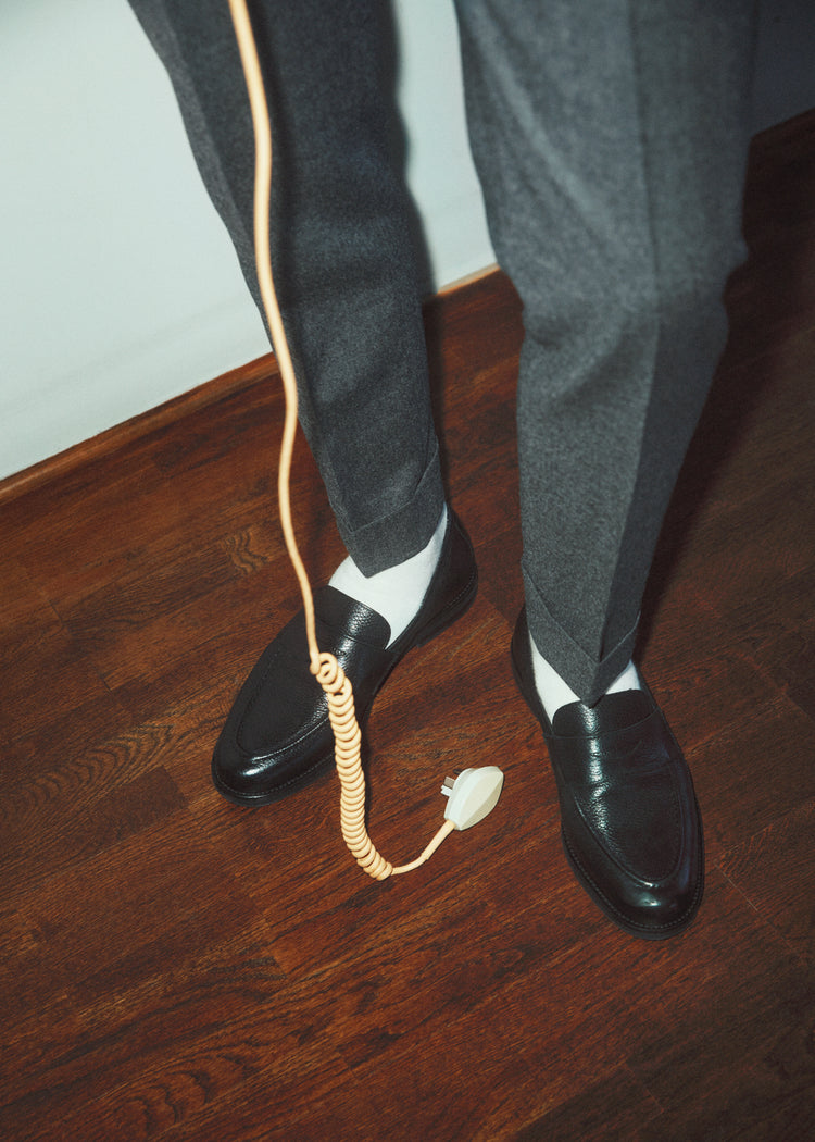 A man with dress shoes and slacks holding a yellow landline.