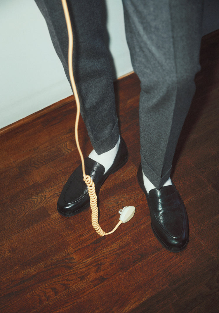 A man with dress shoes and slacks holding a yellow landline.
