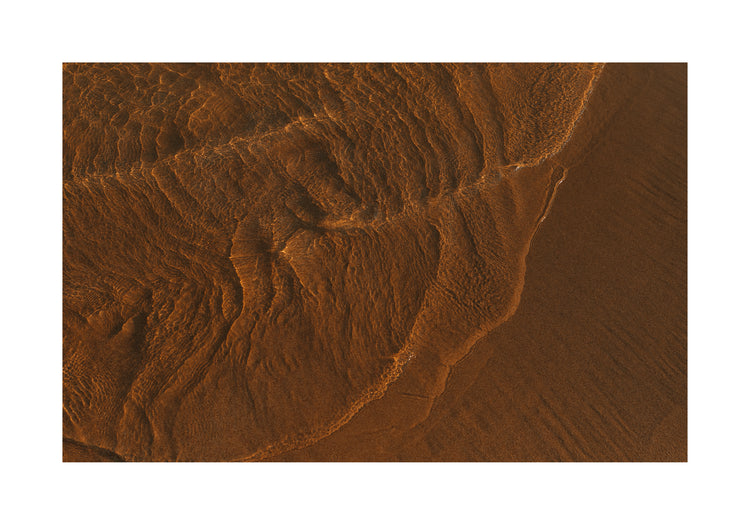 Waves of clear waters softly curling over a sandy shore.