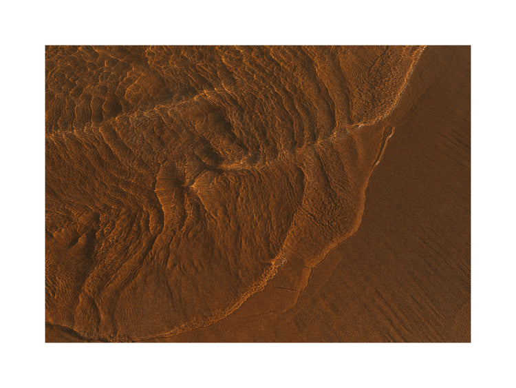 Waves of clear waters softly curling over a sandy shore.