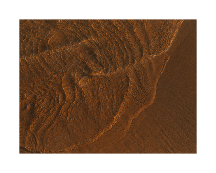 Waves of clear waters softly curling over a sandy shore.