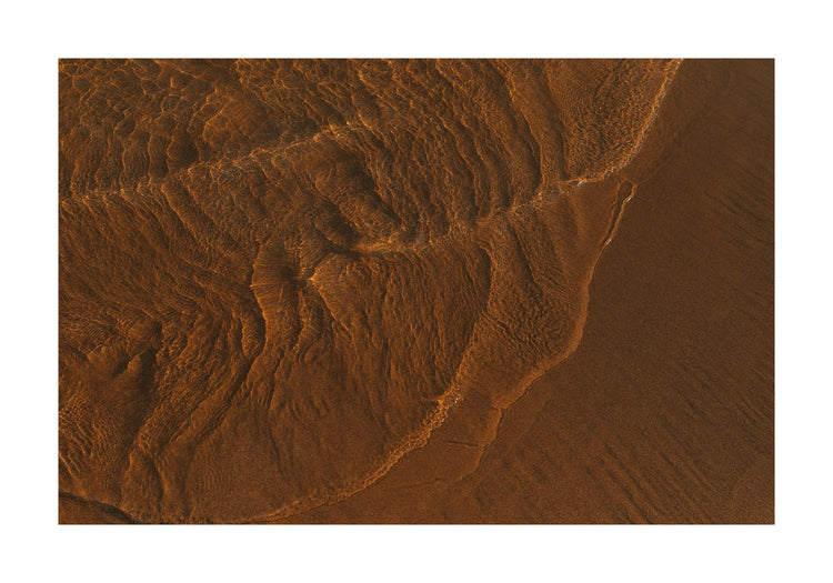 Waves of clear waters softly curling over a sandy shore.