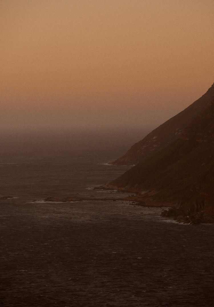 Coastline with a mountain towering along the shoreline during sunrise.