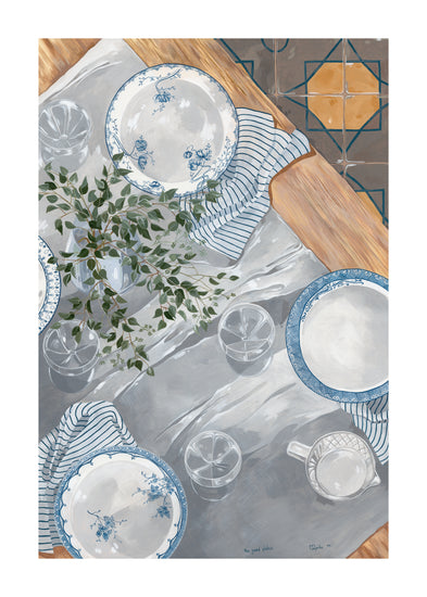 A beautifully arranged table setting by The Good Plates Poster features blue-and-white plates, glasses, and striped napkins on a gray tablecloth with a small leafy plant harmonizing with the decorative floor tiles.