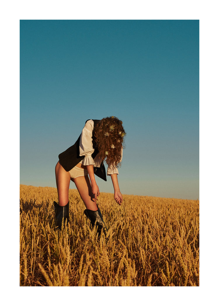 Woman with har full of thistles photographed on a field of wheats.