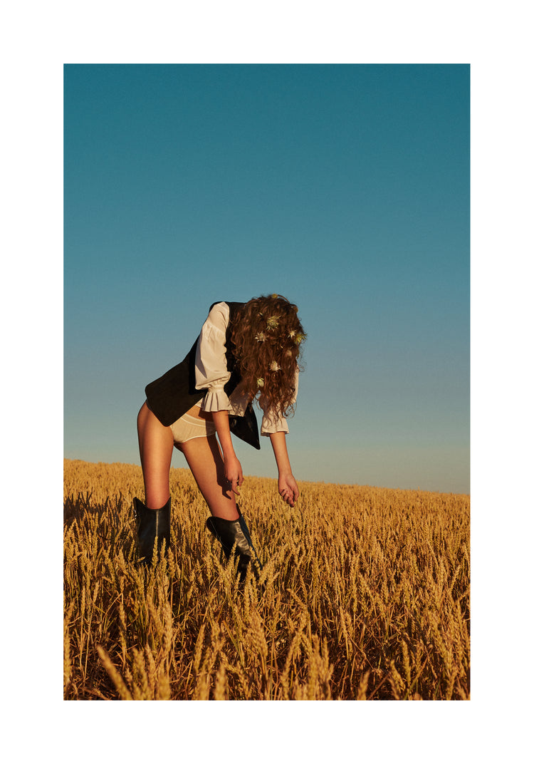 Woman with har full of thistles photographed on a field of wheats.