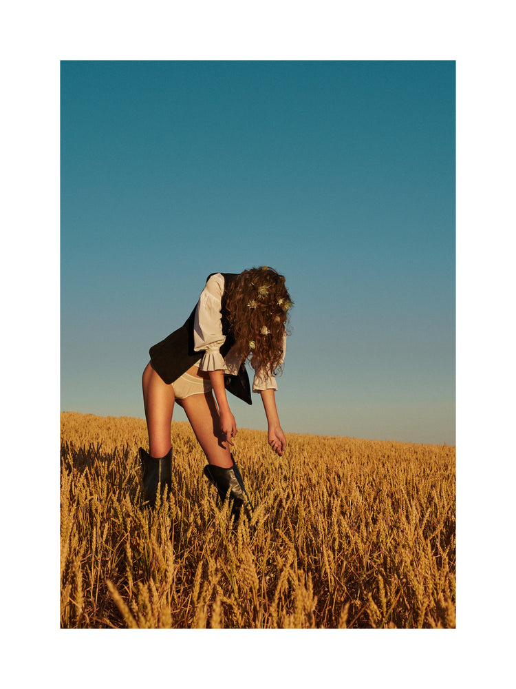 Woman with har full of thistles photographed on a field of wheats.