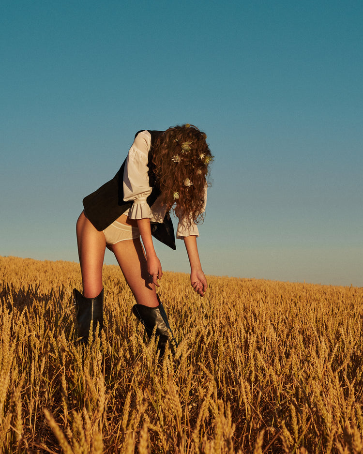 Woman with har full of thistles photographed on a field of wheats.